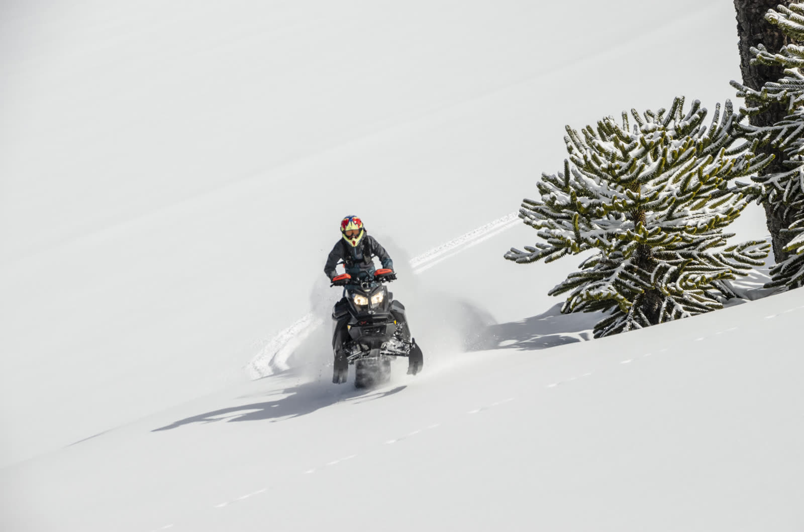 Rider en moto de nieve con skis cargados subiendo la ladera del volcán